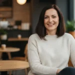 Pewna siebie kobieta w kawiarni, usmiechajaaca sie naturalnie - cechy cenione przez mezczyzn