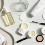 Kosmetyki do double cleansing na marmurowej toaletce z ręcznikiem, wodą i płatkami kosmetycznymi