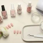 Akcesoria do manicure hybrydowego na marmurowej toaletce z lampą UV LED i lakierami