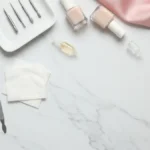 Frezarka, frezy i lakiery nude na marmurowej toaletce do manicure rosyjskiego