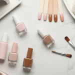 Hybrydy nude, wzorniki paznokci i akcesoria do manicure na jasnym marmurowym blacie
