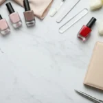 Eleganckie lakiery nude i akcesoria do manicure business na marmurowej toaletce